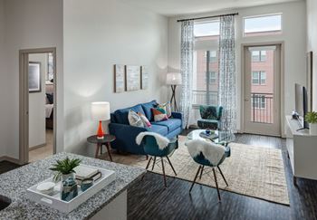 A living room with a blue couch, a chair, and a table with a plant on it at Regatta Sloans Lake Apartments, Denver, Colorado